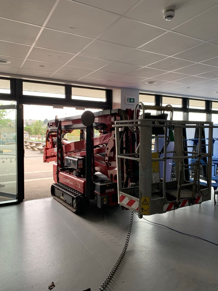 Red tracked spider lift entering a Bradford building for indoor access work