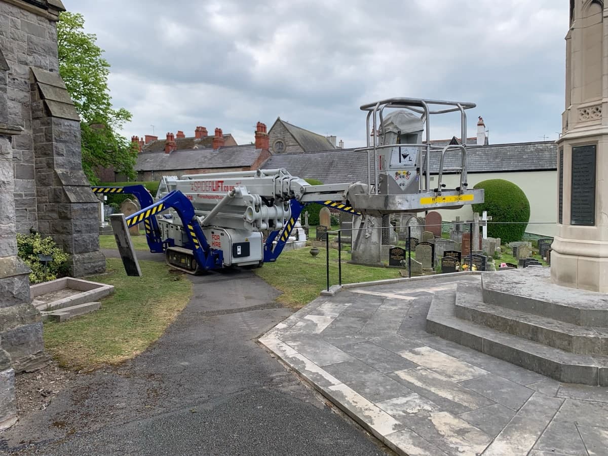 Tracked spider lift positioned on a path through a Prestatyn churchyard
