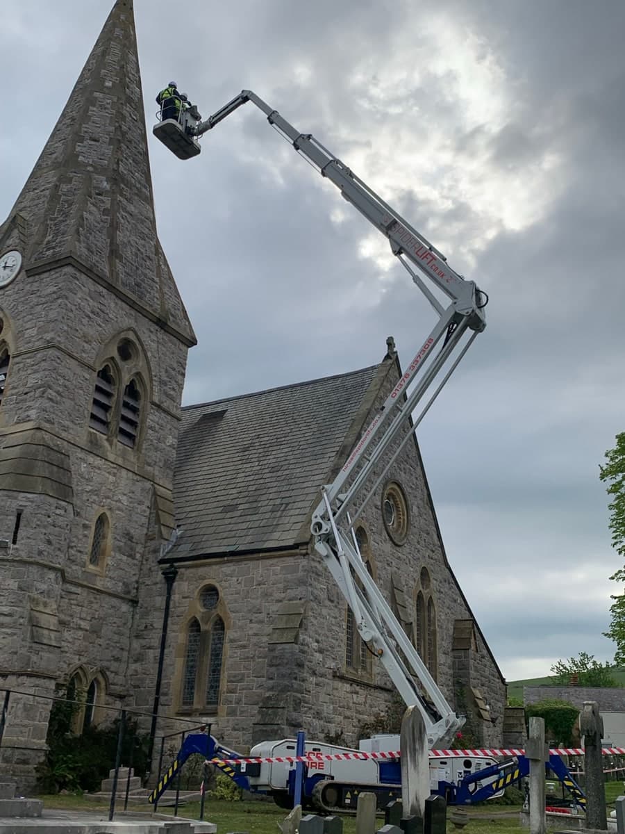 Spider lift boom extended to a stone church spire in Prestatyn