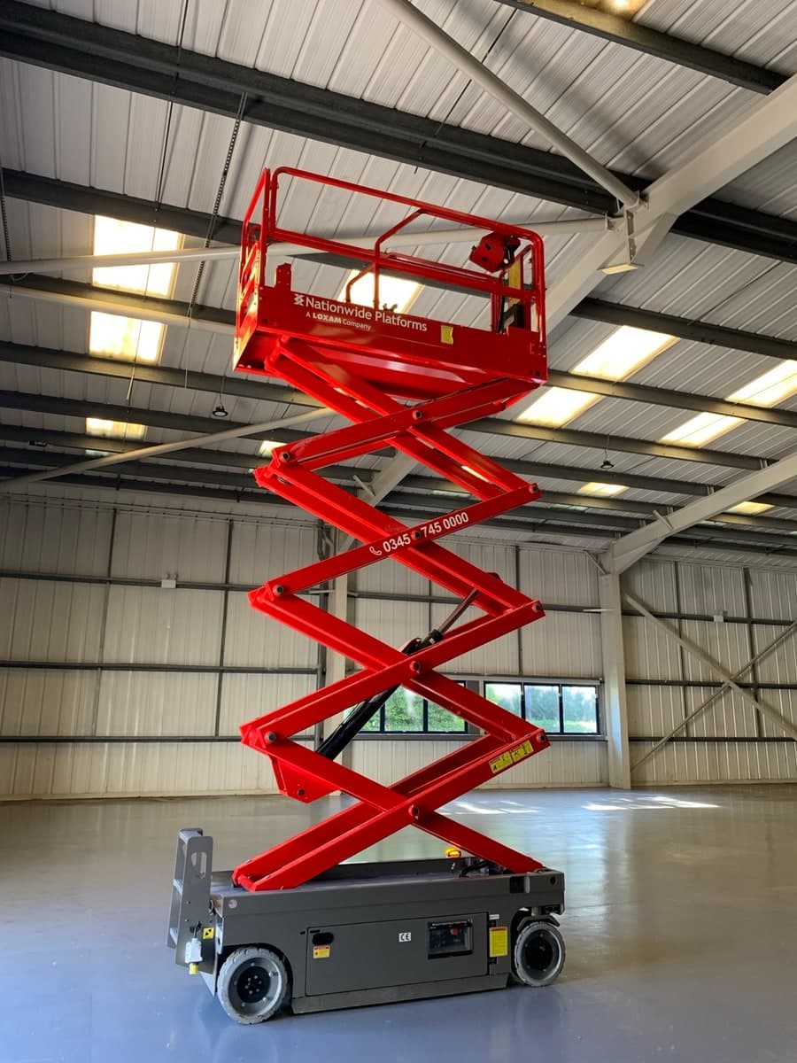 Scissor lift raised towards structural roof steelwork in Warrington